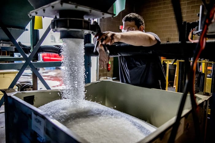 man pouring plastic pellets into bin